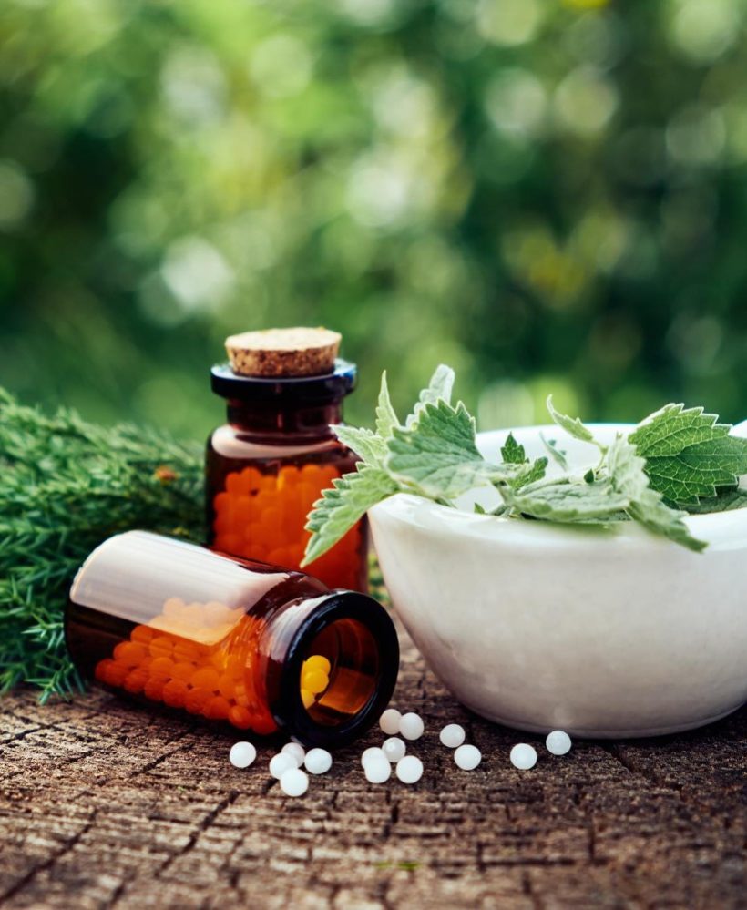 bottle-homeopathic-globules-mortar-green-nettle-mint-leaves-juniper-twigs-homeopathy