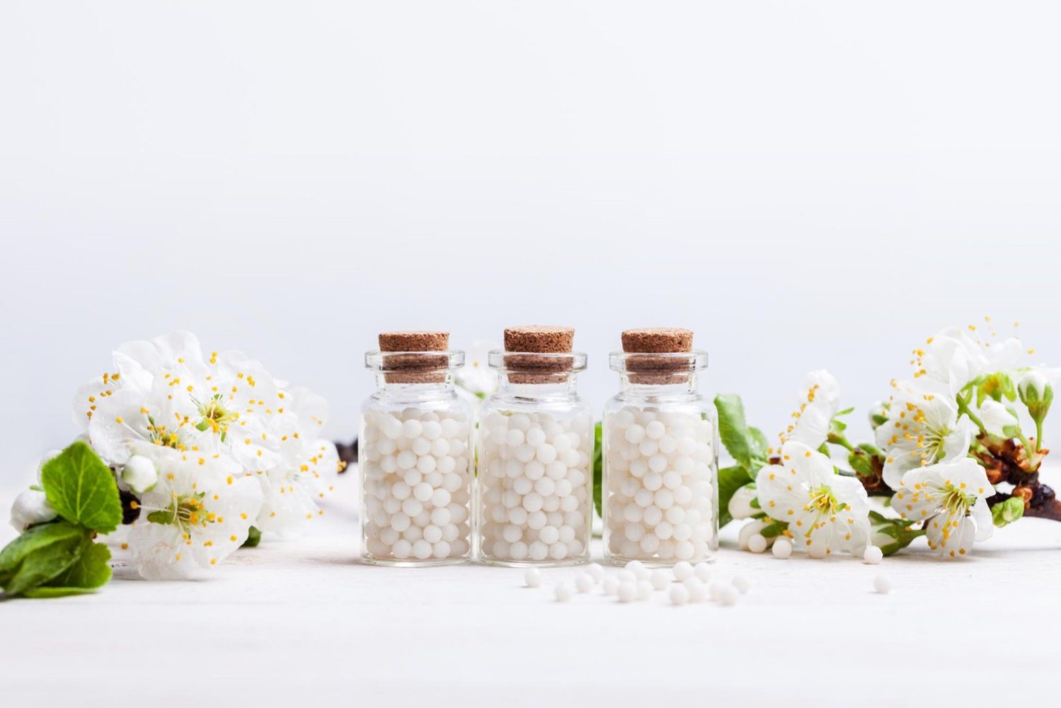 homeopathic-pills-with-spring-flowers-white-wooden-background
